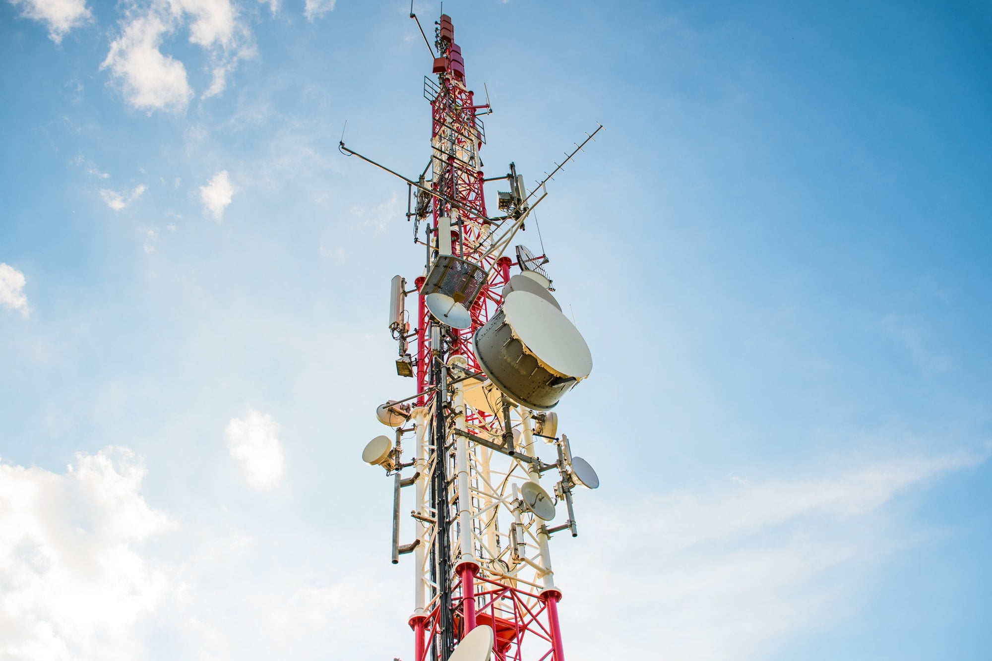 Low angle view of mobile network cell tower against blue sky.